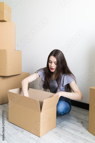 Young woman unpacking moving boxes into new home. Moving into new apartment