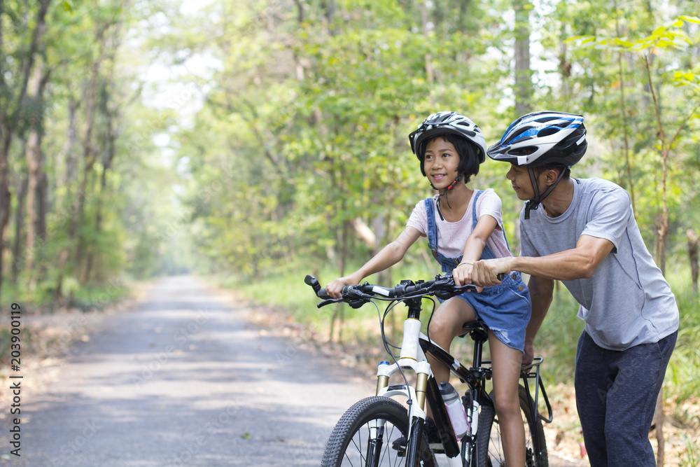 Happy father and daughter cycling in the park, togetherness relaxation concept Happy father and daughter cycling in the park, togetherness relaxation concept