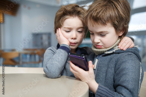 Two little boys play games on the phone. © ksi