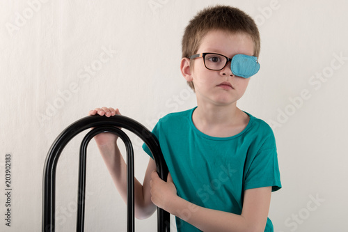 Child in glases with Occluder. .Ortopad Boys Eye Patces nozzle for glasses for treating strabismus (lazy eye) photo