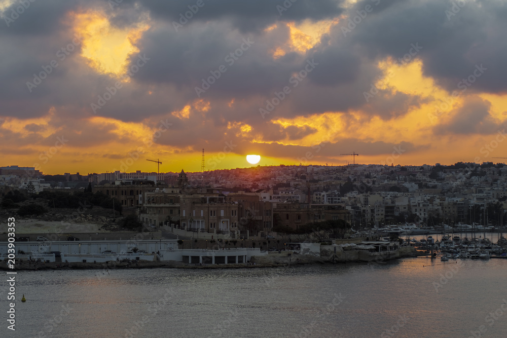 Valletta, Malta sunset in the capital of Malta. Golden hour on cloudy sky over buildings at Gzira area.
