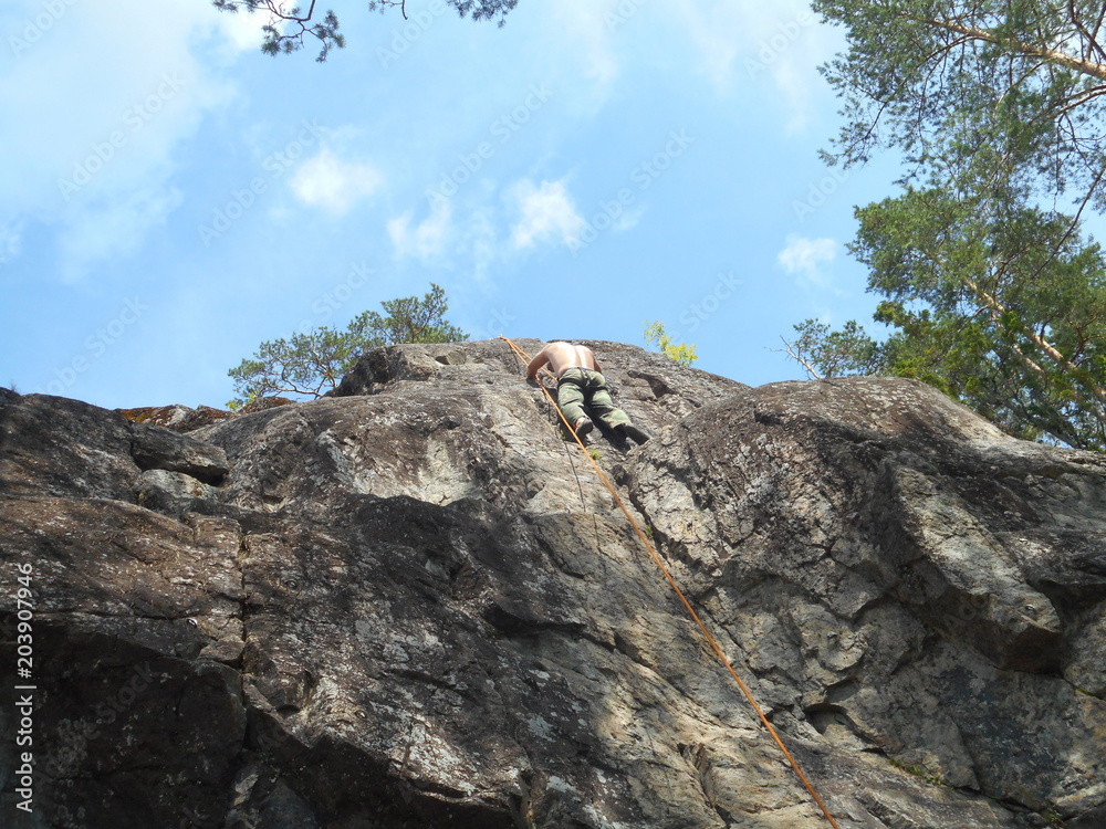 man climbs to the top of the cliff. Top rope climbing.  Karelia. Russia