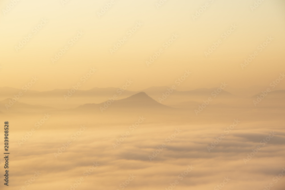 Mountain range with visible silhouettes through the early morning colorful fog.