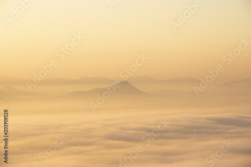 Mountain range with visible silhouettes through the early morning colorful fog.