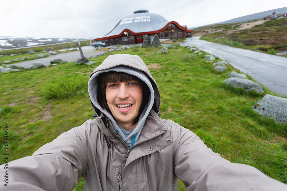 Tourist man making selfie Arctic circle center. Landmark on Lofoten islands. Norway. Tourist man making selfie Arctic circle center. Landmark on Lofoten islands. Norway.