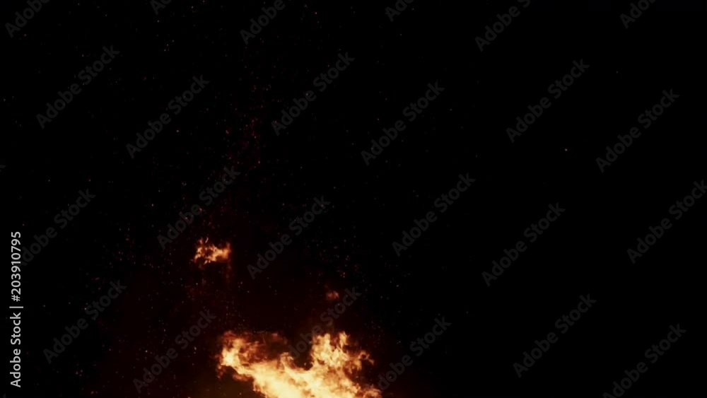 Fragment of burning flame with sparks flying around on black background. Fragment of burning flame with sparks flying around on black background.
