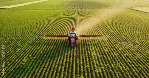 Aerial drone shot of a farmer spraying soybean fields