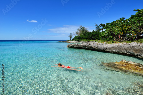 Tourist swimming in turquoise waters of the Caribbean sea on the wild noon coast of Cuba photo