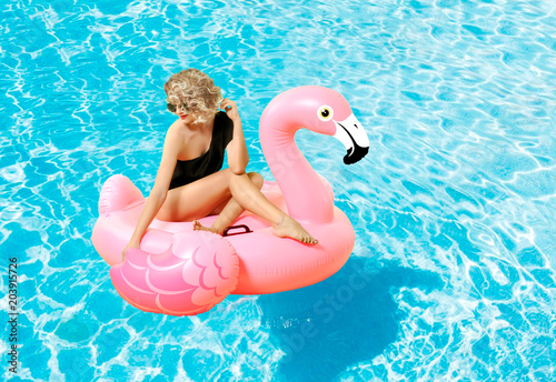 Woman in bikini on the inflatable mattress in the swimming pool.