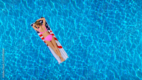 Woman in bikini on the inflatable mattress in the swimming pool. © Dmytro Flisak