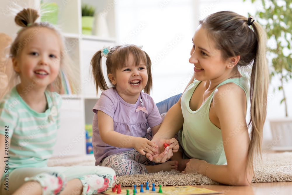 Fototapeta premium Mother and her children playing in ludo board game