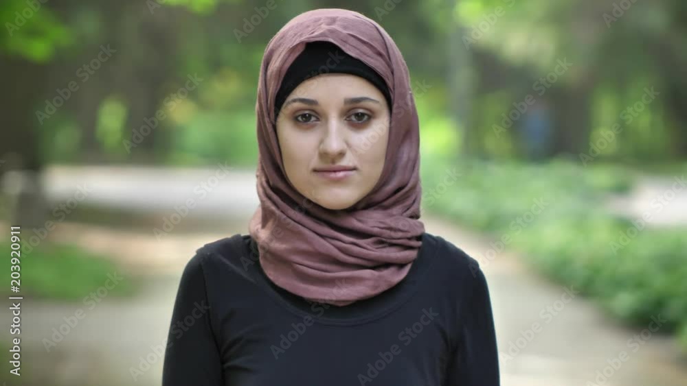 Portrait of a young sad girl in hijab, outdoor, in a park in the background. 50 fps Portrait of a young sad girl in hijab, outdoor, in a park in the background. 50 fps