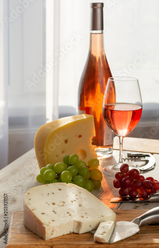 Dutch hard cheese Maasdam or Emmentaler, cheese with holes and white hard goat cheese with coriander served with rose wine