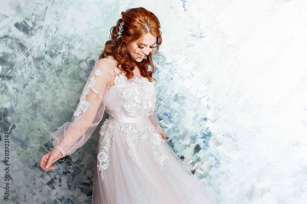 Beautiful and romantic bride in wedding dress with long sleeves. Young redheaded woman in wedding dress Beautiful and romantic bride in wedding dress with long sleeves. Young redheaded woman in wedding dress