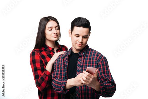 Woman hugs man that looking on smartphone screen