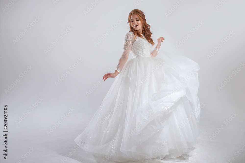 Lovely young woman bride in lavish wedding dress. Light background.