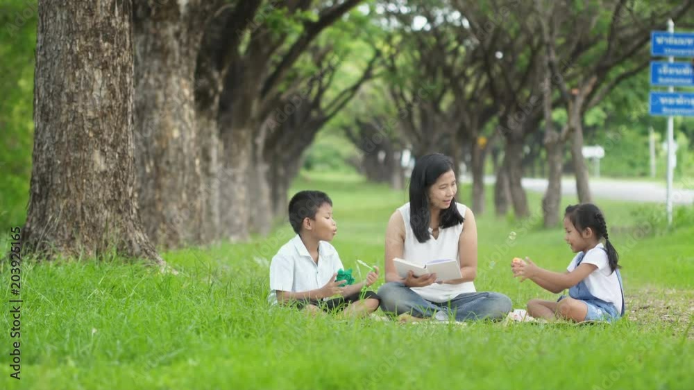 Happy family, Mother daughter and son joint a activities by blow bubbles and read book in garden. Happy family, Mother daughter and son joint a activities by blow bubbles and read book in garden.