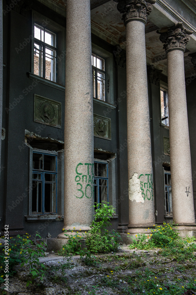 Naklejka premium DESTROYED FORMED OLD ADMINISTRATIVE HOUSE IN THE CITY ENVIRONMENT. REMAINS OF WALLS, STAIRS AND WINDOWS.