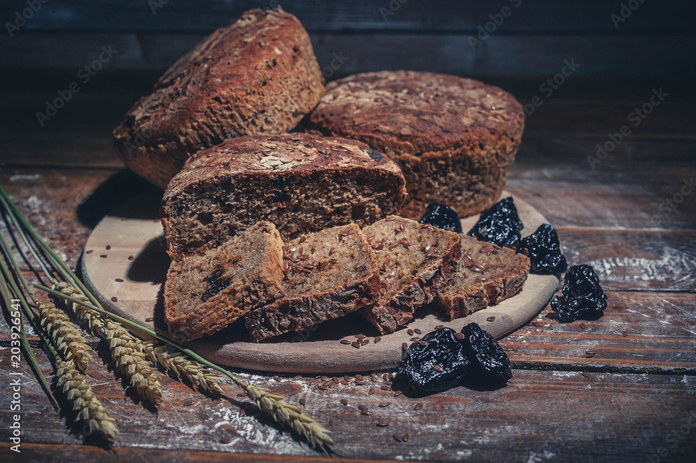 Rye bread with flax seeds and prunes on a wooden background. Homemade baking. Low key lighting. Light toning
