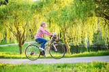Beautiful senior woman with bicycle outside in spring nature.