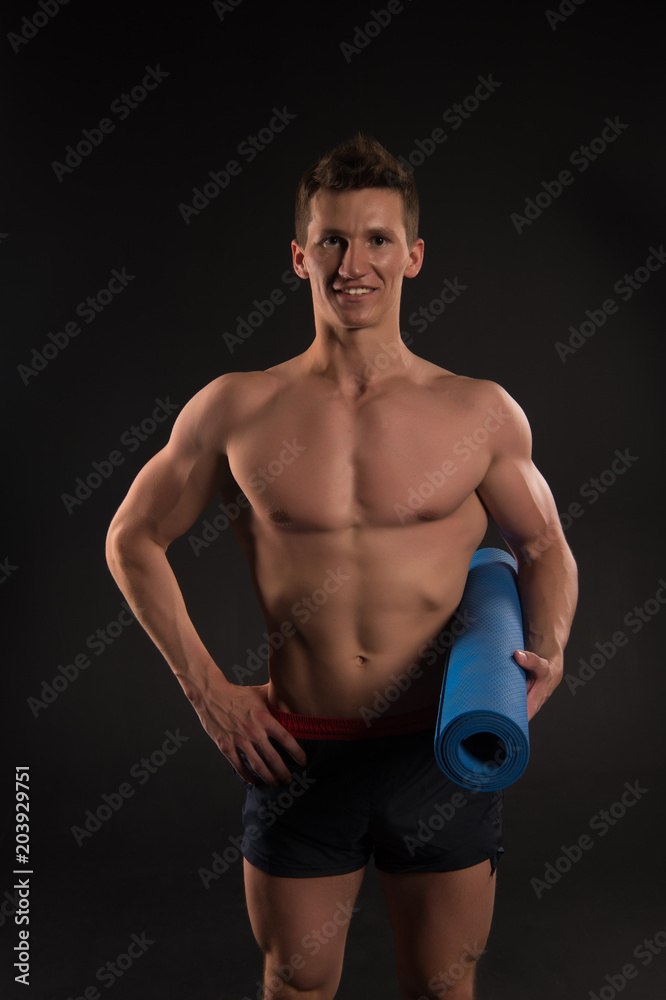 Sportsman smile with sexy torso and six pack. Happy man hold yoga mat. Athlete smiling with strong arms in shorts. Gym equipment for training and workout. Sport yoga and fitness activity Sportsman smile with sexy torso and six pack. Happy man hold yoga mat. Athlete smiling with strong arms in shorts. Gym equipment for training and workout. Sport yoga and fitness activity
