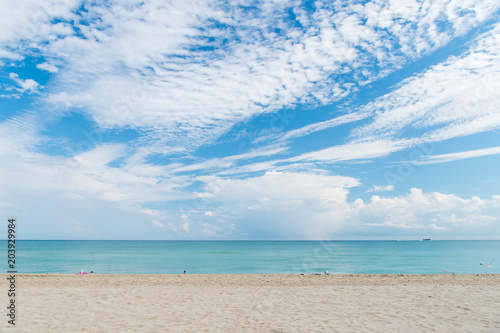 Fototapeta Naklejka Na Ścianę i Meble -  Sea beach with white sand and blue water in miami, usa. Seascape on cloudy sky. Summer vacation on tropical resort. Discovery or adventure and wanderlust