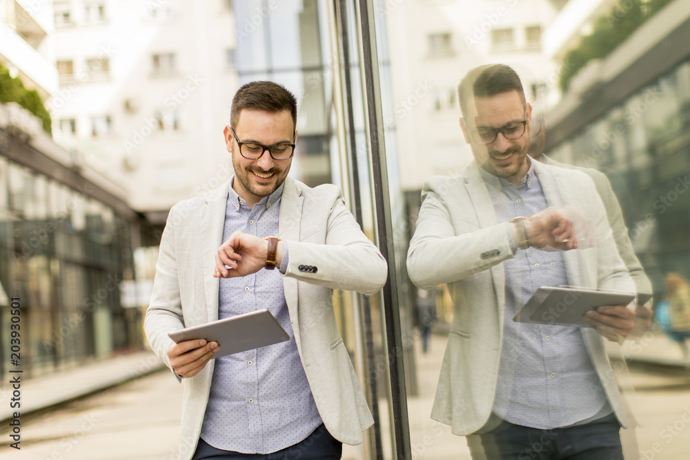 Young businessman with digital tablet by the office building