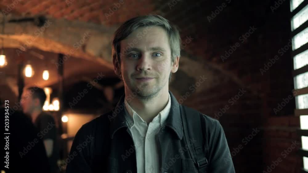 Indoor shot of happy young bar owner standing at the counter and looking away smiling, man bartender beer pub Indoor shot of happy young bar owner standing at the counter and looking away smiling, man bartender beer pub