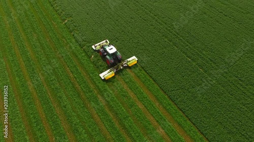 Aerial view of a tractor mowing a green fresh grass field, 
a farmer in a modern tractor mowing a green fresh grass field on a sunny day.