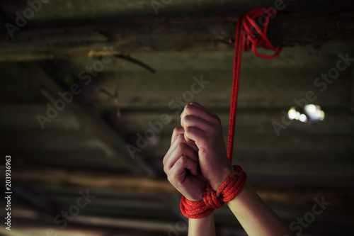 Fotografi Closeup hostage hands tied by red rope