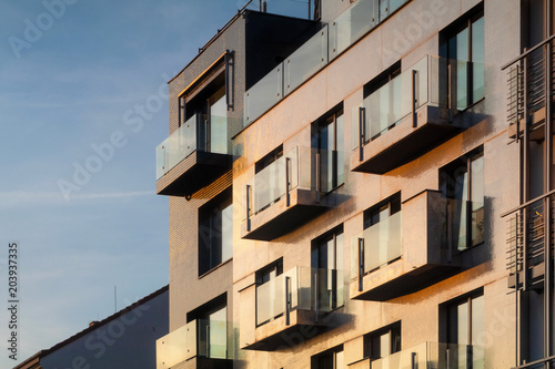 Golden facade of a multistorey building with balconies, background at the sunset © Kennymax