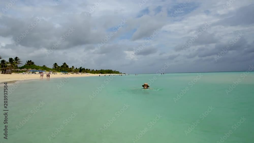 woman in a straw hat floats in the ocean near the beach woman in a straw hat floats in the ocean near the beach