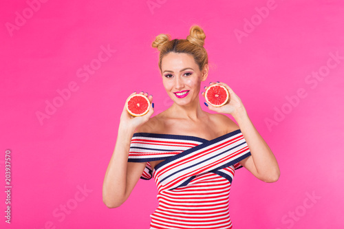 Portrait of happy girl holding halves of orange near face