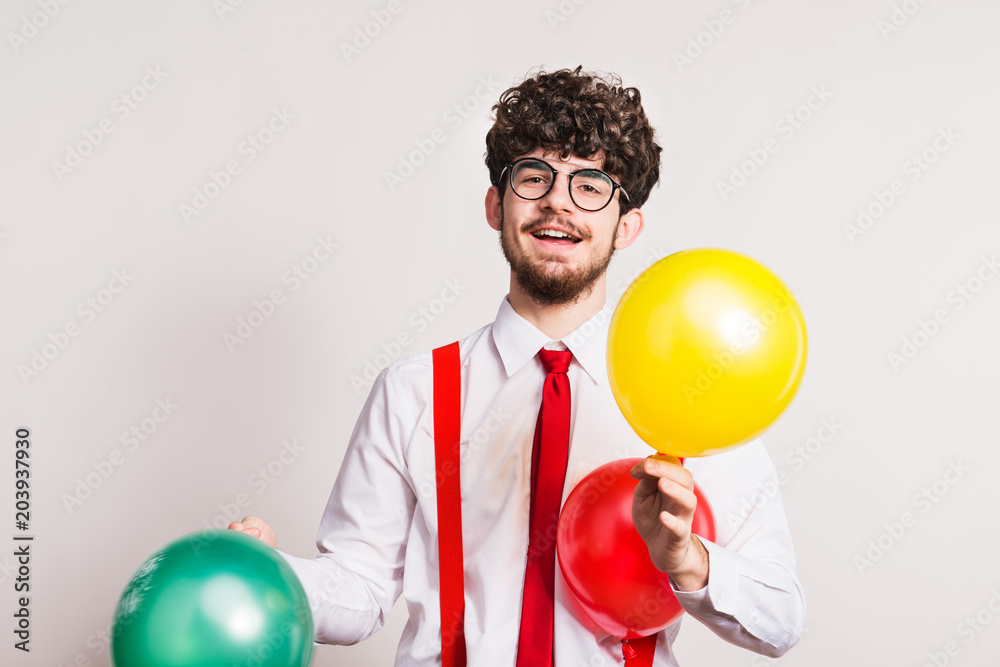 Portrait of a young man with balloons in a studio. Portrait of a young man with balloons in a studio.