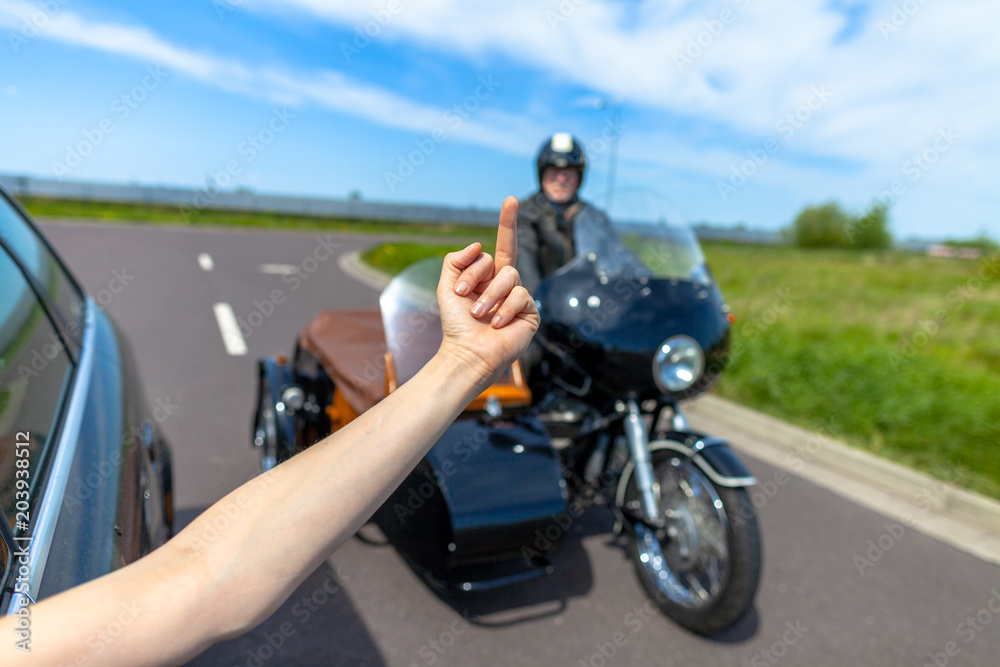 a car driver shows his middle finger to a biker a car driver shows his middle finger to a biker