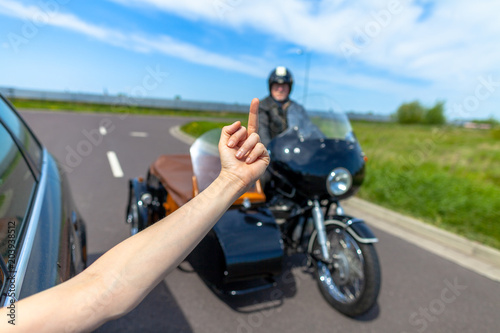 a car driver shows his middle finger to a biker