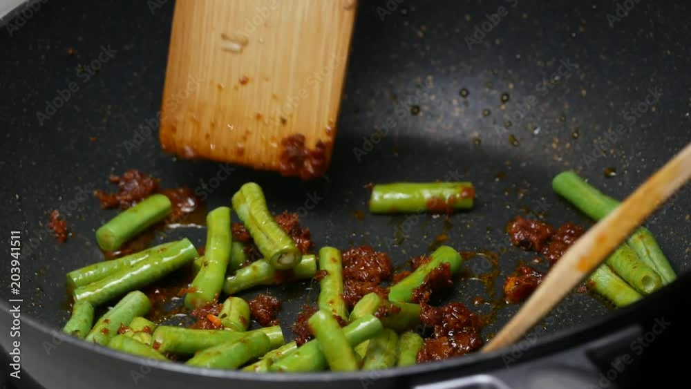 stir fried yard long beans , the spices , curry paste  , food palm oil  together in the black teflon pan and with wooden turner.