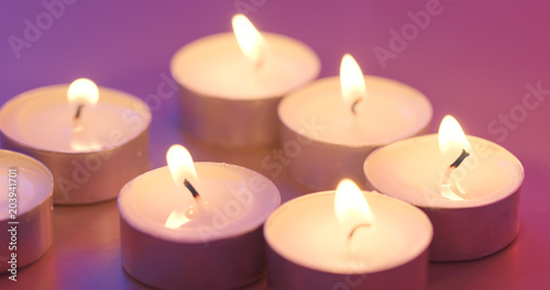 Burning candle under purple and blue light