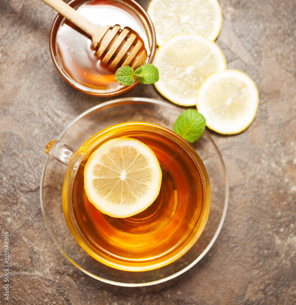 A cup of tea with lemon and honey on a wooden background A cup of tea with lemon and honey on a wooden background