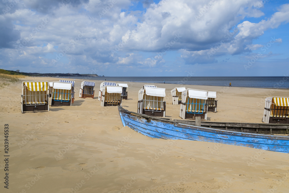Verlassene Strandkörbe mit blauem Boot an der Ostsee