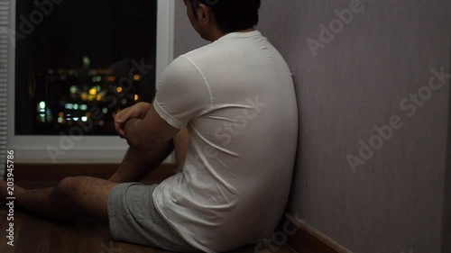 Man sitting at window, looking depressed and sad at night