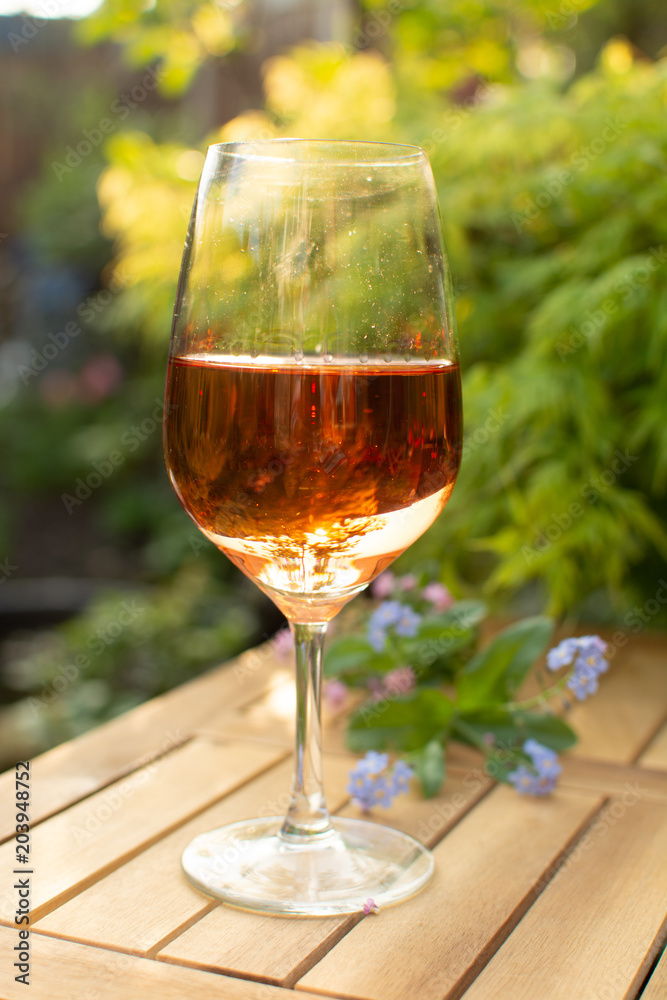Trendy orange wine served on outdoor terrace in garden with flowers Trendy orange wine served on outdoor terrace in garden with flowers