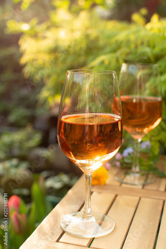 Trendy orange wine served on outdoor terrace in garden with flowers