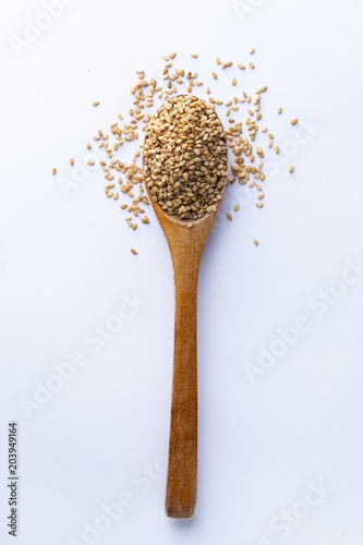 Spoon full of sesame grains on white background