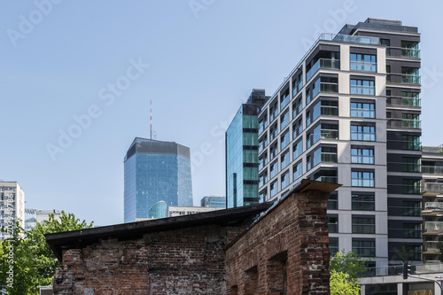 Architecture - old red brick house and modern glass skyscraper in the former Jewish quarter in the residential district called Behind the Iron Gate in Wola district on a sunny day. Warsaw Poland