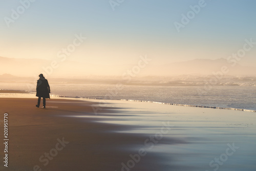 lonely person walking on beach at sunset photo