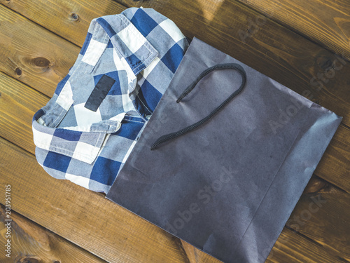 new checkered shirt pop out from shopping bag on a wooden background