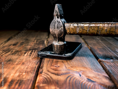 close up a hammer crashing a phone on a wooden surface