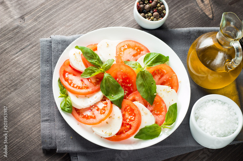 Close-up photo of caprese salad with ripe tomatoes, basil, buffalo mozzarella cheese. Italian and Mediterranean food concept. Fresh and healthy organic meal. Starter and antipasti. 