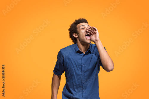Isolated on blue young casual man shouting at studio